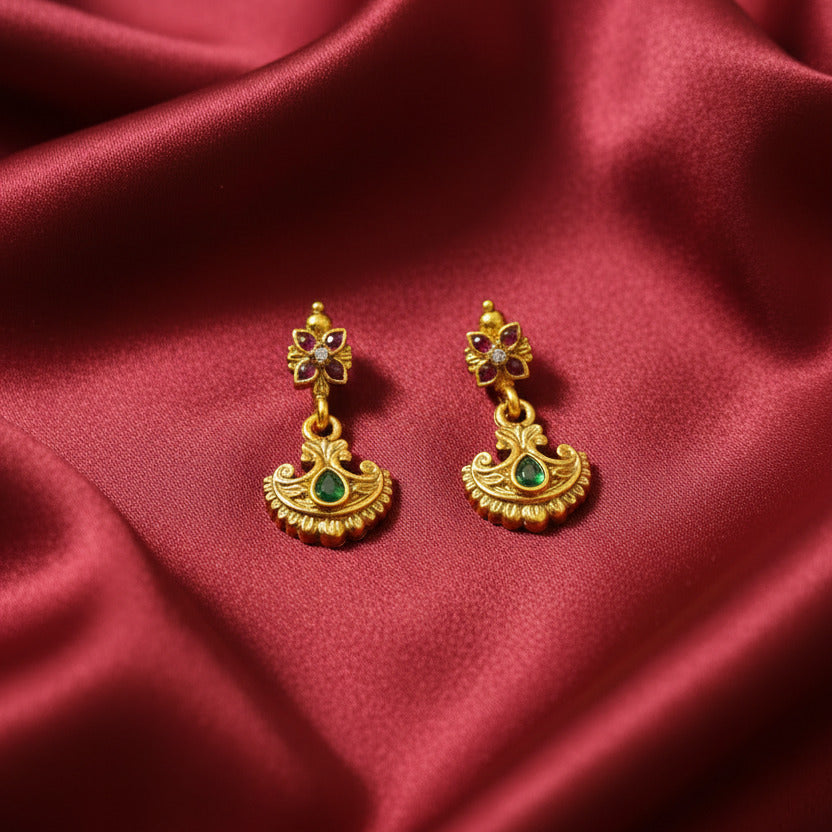 Gold jewelry set with earrings and necklace on a black stand